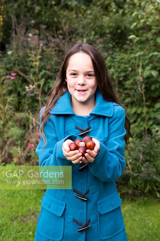 Young girl holding conkers