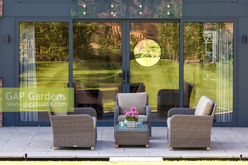 A patio area, with seating and a rill, in a modern Cheshire country garden. It was designed by Louise Harrison-Holland and was photographed in August.