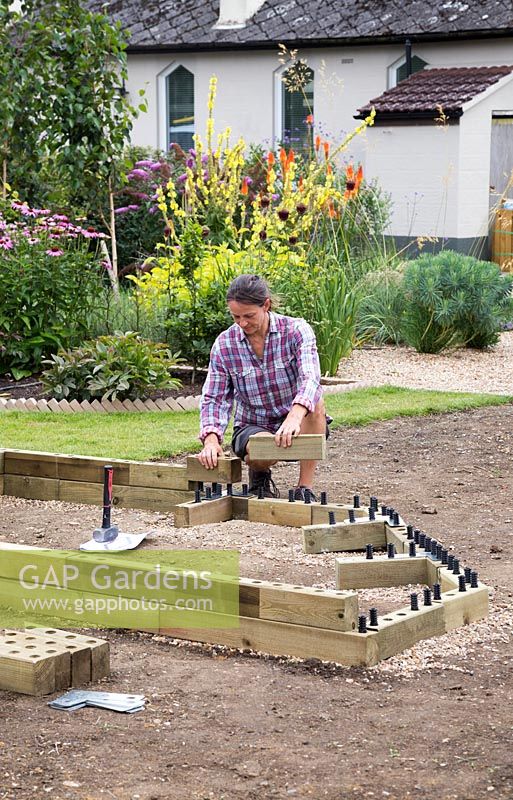Woman adding the second layer of wooden blocks onto the raised bed
