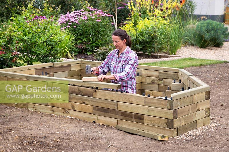 Woman hammering final wood pieces to raised bed