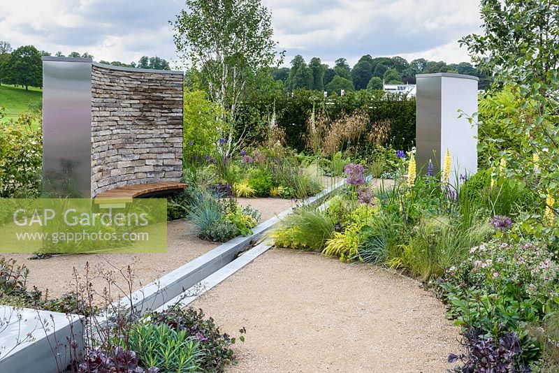 Dry stone wall, wooden bench, water feature rill channel and beds of herbaceous perennials, grasses, shrubs and trees - Cruse Bereavement Care: 'A Time for Everything' - RHS Chatsworth Flower Show 2017 - Designer: Neil Sutcliffe - Sponsor: London Stone