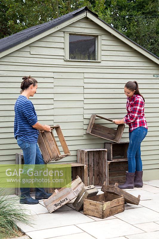 Woman and young girl planning arrangement of vintage crate storage