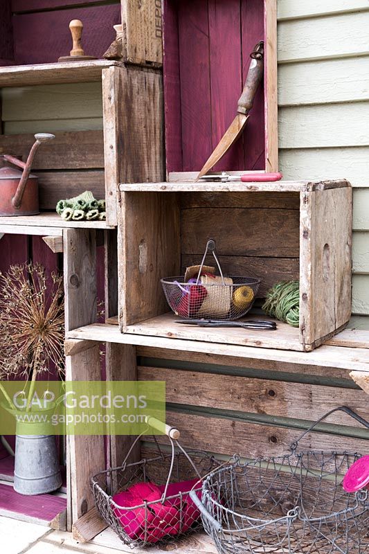 Vinatge crate storage with wire baskets, garden tools and Allium seed heads