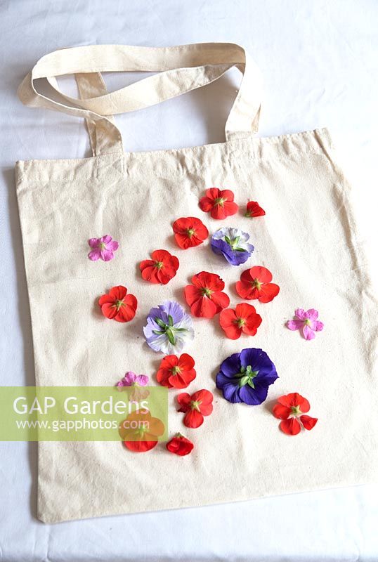 Printing onto fabric bag with fresh flowers. Remove the stems from the flowerheads and lay the flowers face down on to your bag in the pattern you want.