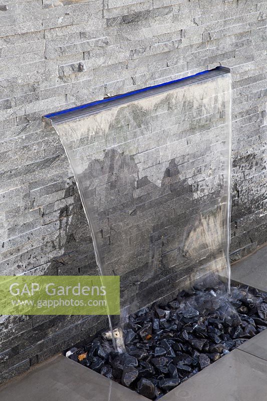 Wall mounted water feature and stone cladding in modern garden
