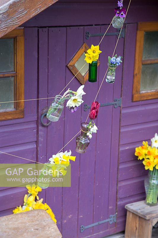 Small vases with flowers tied on string as bunting