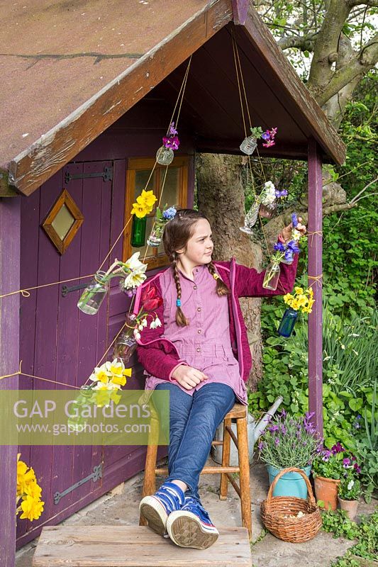 Young girl sat in front of decorated playhouse