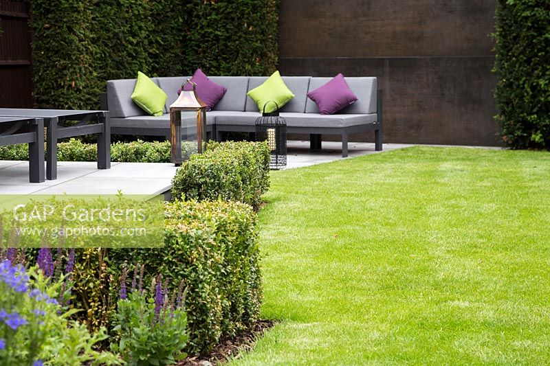Contemporary suburban garden with corner sofa and feature wall