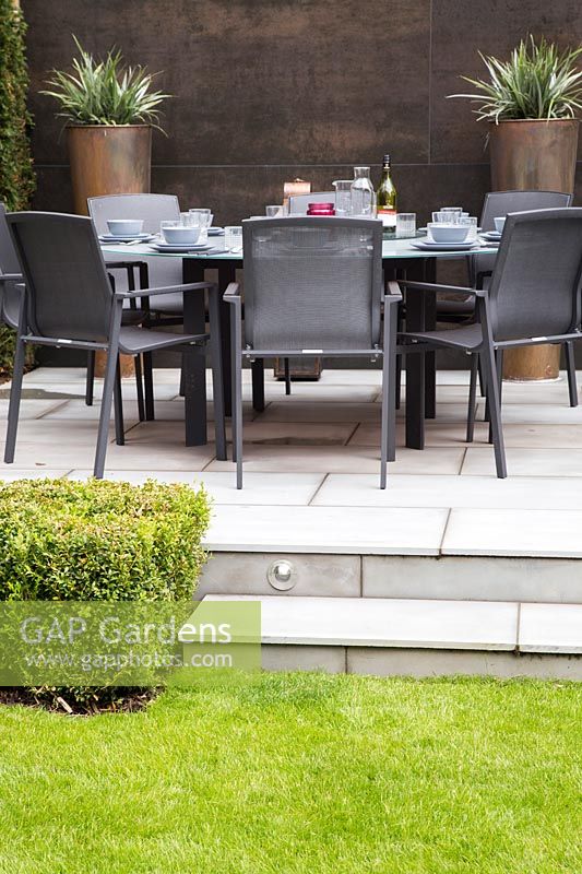 Dining furniture and sun loungers on contemporary patio in subrban garden