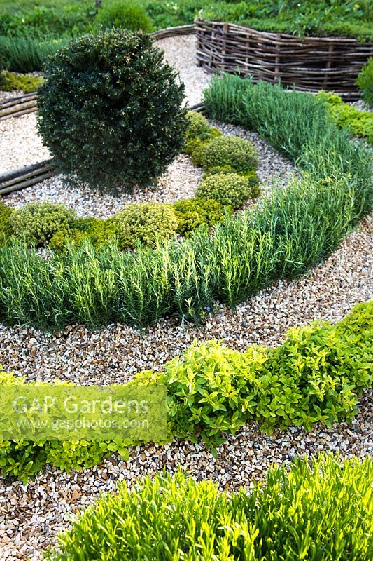Formal garden with Taxus baccata topiary and herbs separated with gravel and woven boundary. Bridgend College: The Life of a Hermit. Designer: Matthew Joseph, RHS Cardiff Show 2017