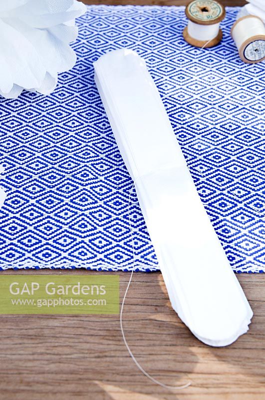 Making a paper pom pom from napkins. Trim the corner of the fastened napkin strip in to a round scalloped shape
