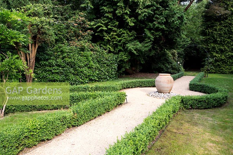 Buxus sempervirens hedge lining a gravel path with terracotta pot in a Tom Hoblyn designed garden at Heatherbrae