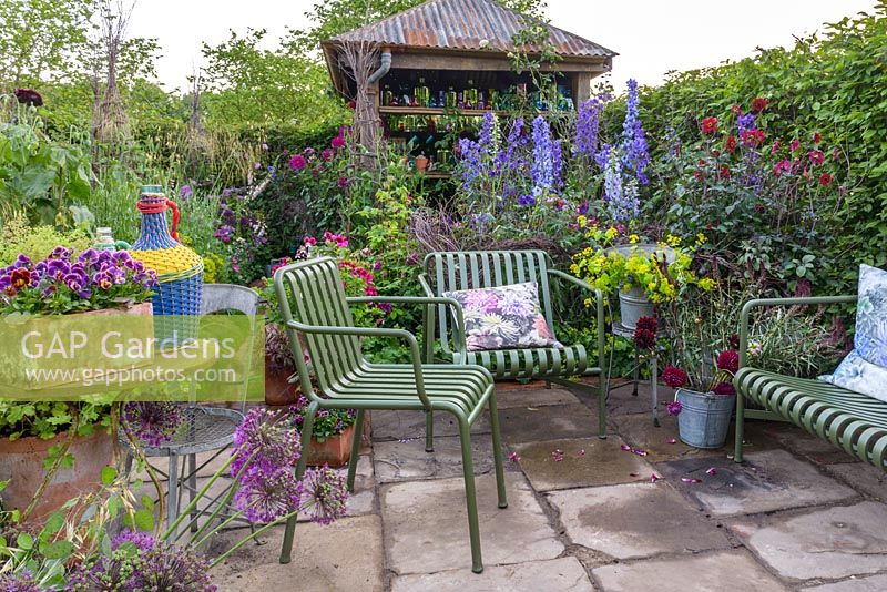 The Anneka Rice Colour Cutting Garden - Seating area with meatl chairs and bench in front of shed. Radio 2 Feel Good Gardens- RHS Chelsea Flower Show 2017 