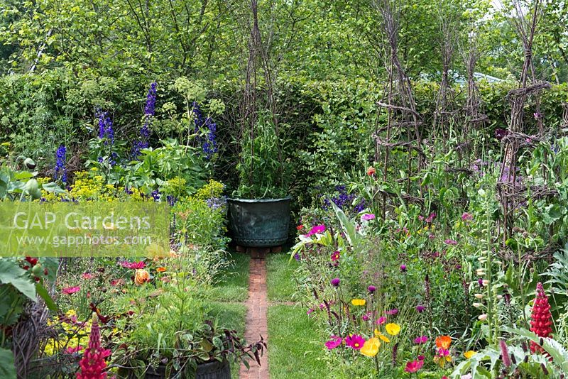 The Anneka Rice Colour Cutting Garden - Narrow brick paths separate beds brimming over with sweet peas on birch obelisks, roses, cosmos, euphorbia, delphinium, lupins and angelica - RHS Chelsea Flower Show 2017