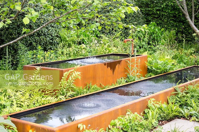 Water bouncing caused by speakers playing music  underground. Rusted corten steel tanks with ferns surrounding - BBC Radio 2 Feel Good Gardens - The Zoe Ball Listening Garden, RHS Chelsea Flower Show 2017 - Designer: James Alexander-Sinclair  - Sponsor: RHS