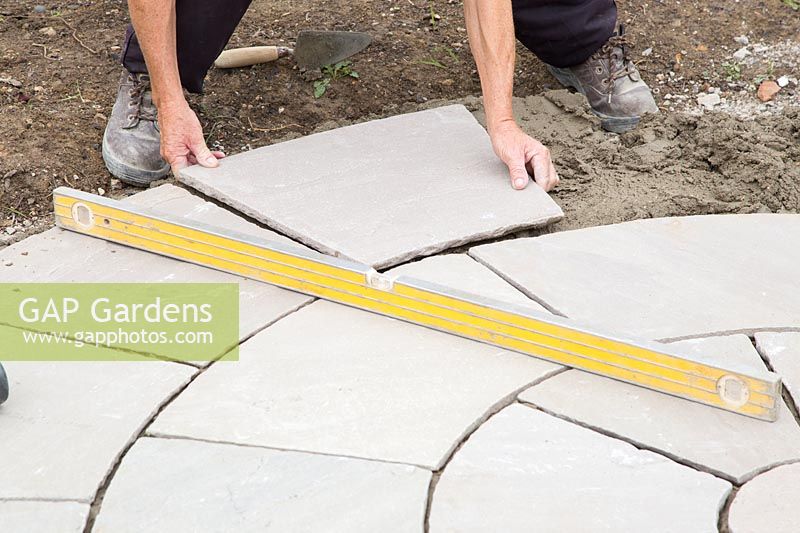 Man laying slabs in centre of circular patio