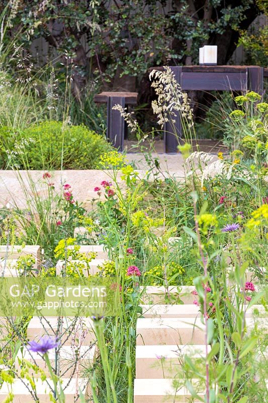 The M and G Garden - limestone blocks in a garden inspired by the Mediterranean landscape of Malta. This part mimics the climate and diversity of the garrigue, and includes euphorbias, woad, valerian and grasses -RHS Chelsea Flower Show 2017