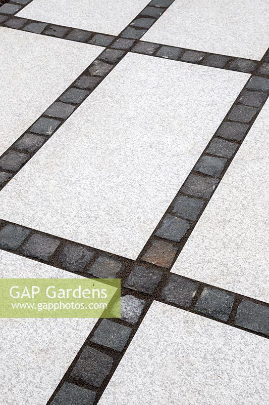 Making a mixed material patio - detail of paving where large porcelain slabs are mixed with granite setts