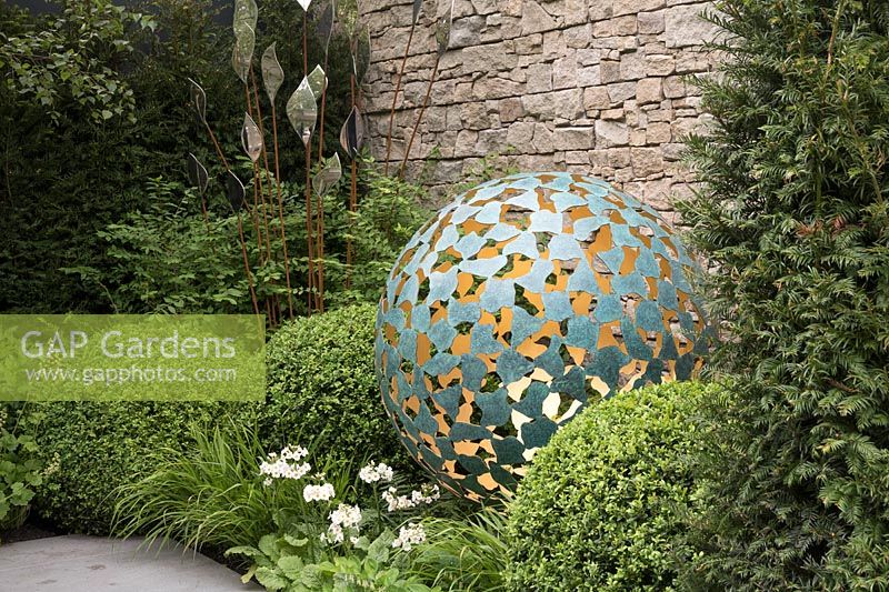 Round sculpture lit from the inside in a bed of box and primulas - RHS Chelsea Flower Show 2017