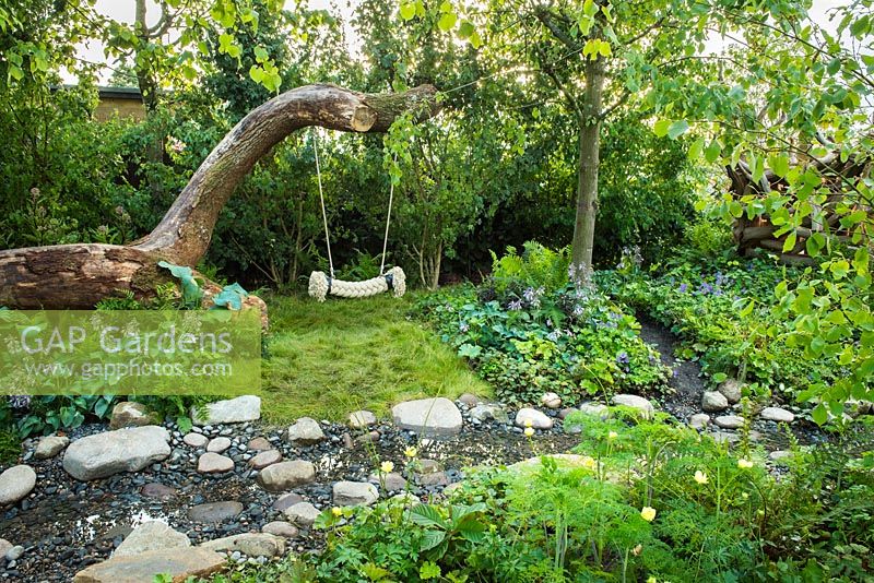 Tree rope swing in wild garden next to the  stream with stones - The Zoflora and Caudwell Children's Wild Garden, RHS Hampton Court Palace Flower Show 2017