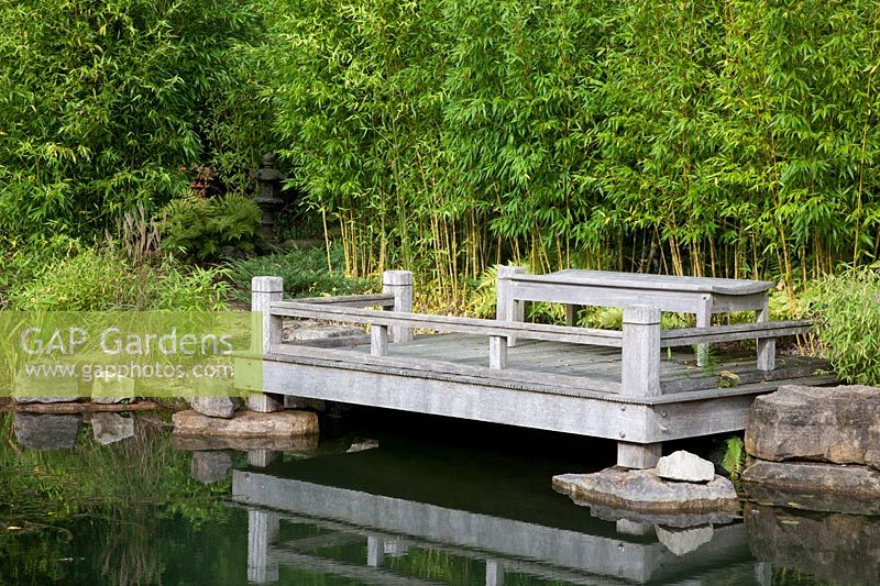 A Japanese style garden  with oak deck jetty overlooking pond,  Bamboo, pathway to hidden stone temple ornament -  Brightling Down farm