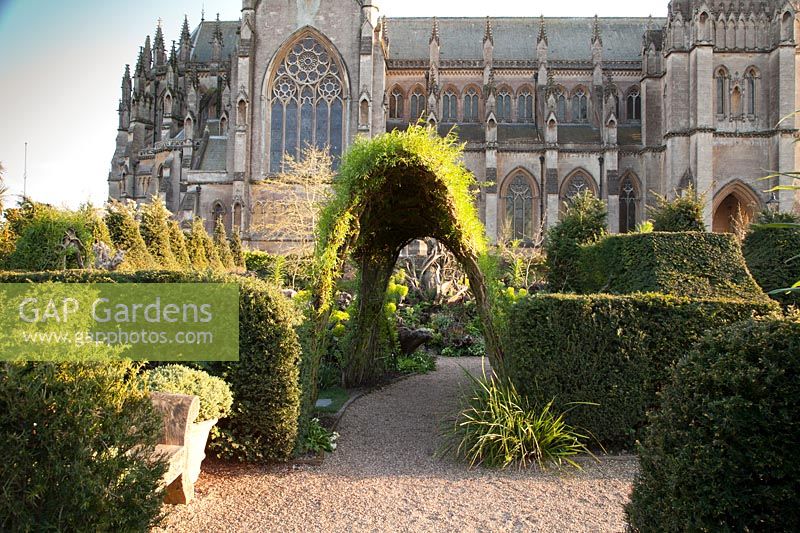 Walled garden with clipped yew hedges and decorative archway with cathedral beyond at Arundel Castle, Sussex in spring. Head Gardener: Martin Duncan