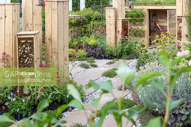 Front garden with bug hotels and bicycle shed made form wooden pallets with gravel and stone path with drought resistant plants - BBC Gardener's World Live, Birmingham 2017 - Artemis Landscapes 'Living in Sync'  Garden - Designer: Viv Seccombe
