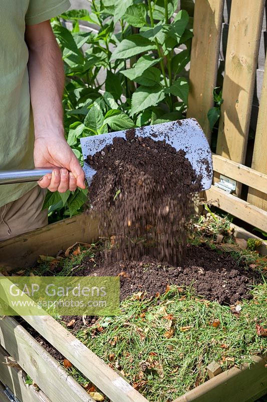 Adding soil to grass clippings in compost to maintain balance and help rot, June