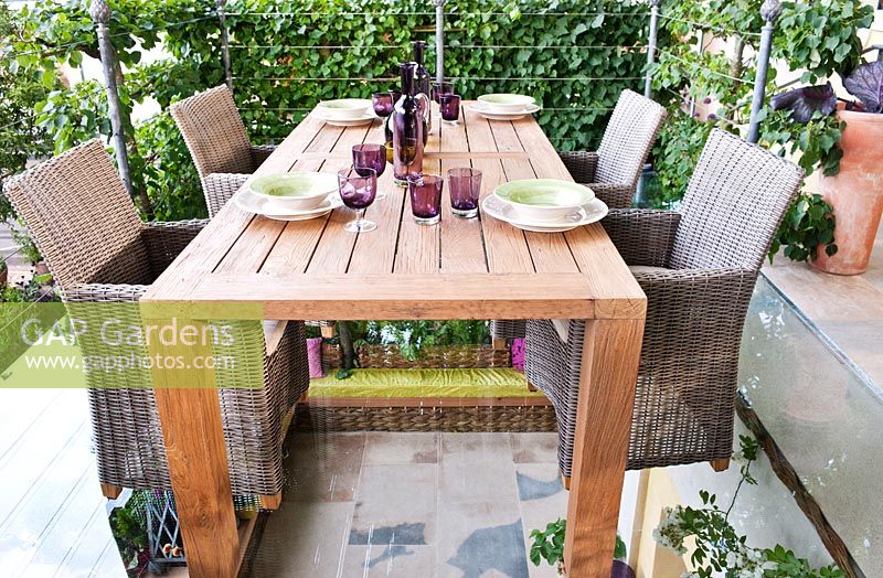 Wooden table set for a meal with wicker chairs, RHS Chelsea 2011, May.