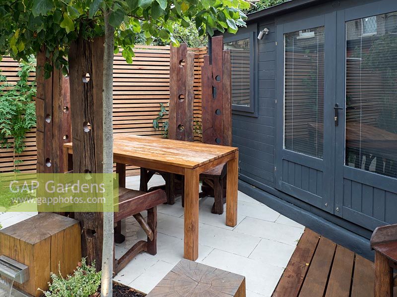 Large reclaimed teak tables and chairs in small garden, September.