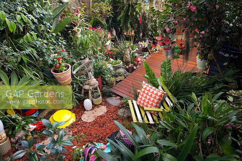 Timber deck, pots and garden ornaments with shade loving plants, June.