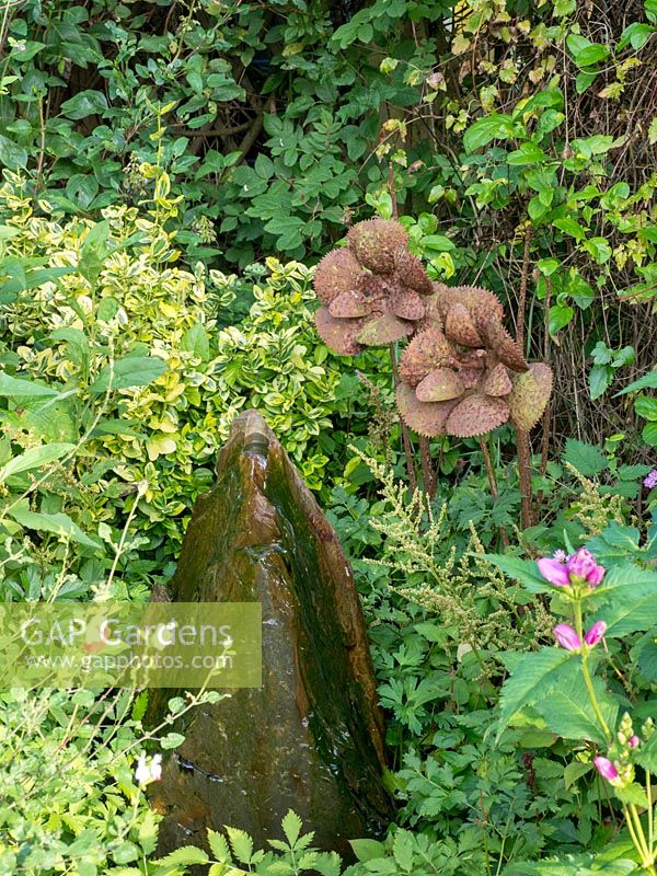 Rock water feature and two steel flowers