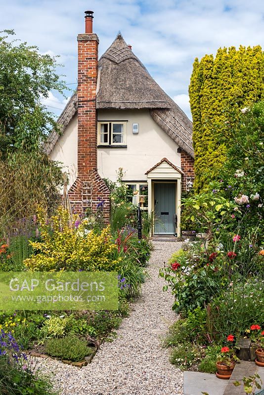 A gravel path edged in perennials leads to Caynton Cottage, a seventeenth century thatched cottage.