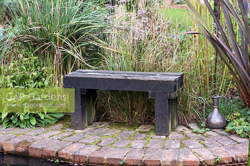 A small wooden bench on brick surround to pond.