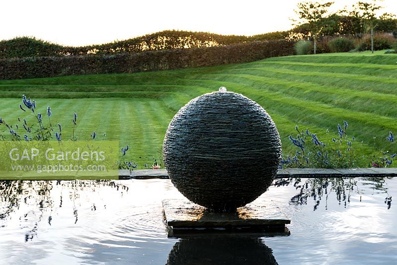 Slate sphere water feature created by sculptor James Parker with grass terraces inspired by  gardens of Charles Jencks.