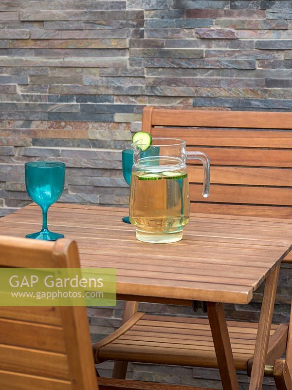 Jug and glasses on wooden table in urban garden
