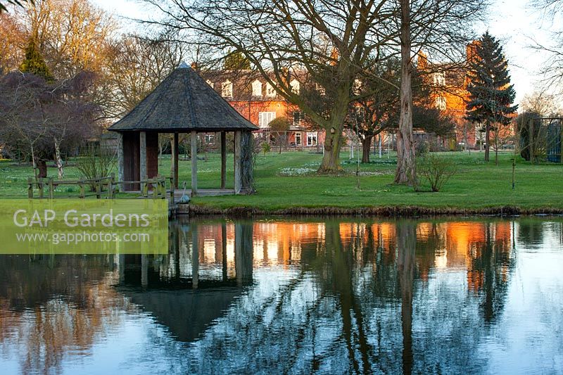 House and summerhouse reflected in lake, Chippenham Park, Cambridgeshire.