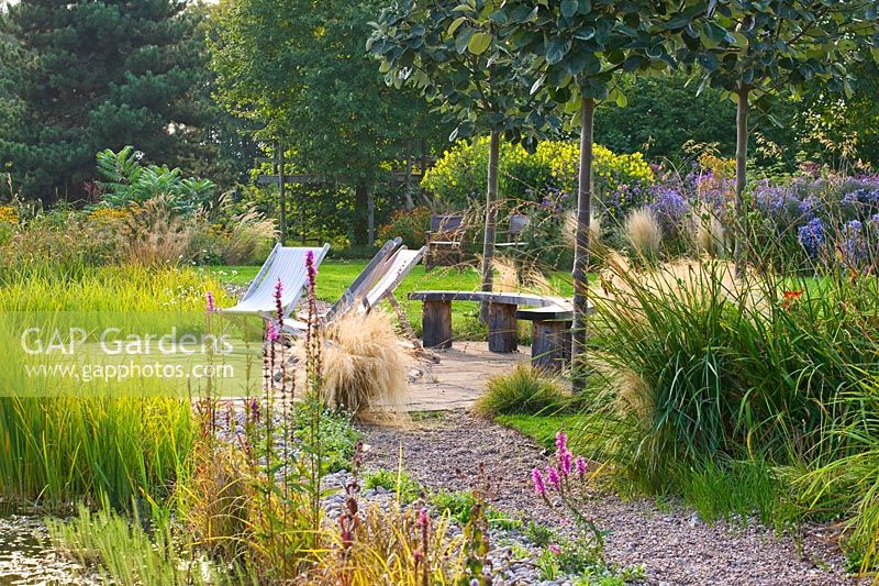 View along gravel path to patio with seating and grass beds