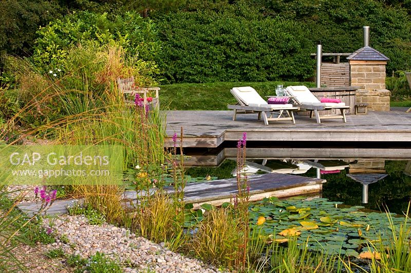 'Natural' swimming pool with marginal planting and waterlilies. Surrounded by gravel path plus wooden jetty. Also seating and entertaining space.