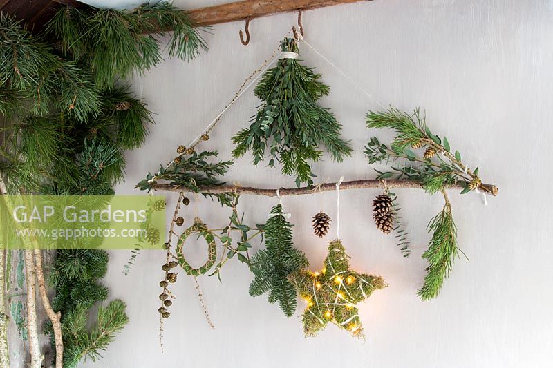 Natural material Christmas decorations - branch decorated with stars, wreath, foliage and LED lights in rustic setting