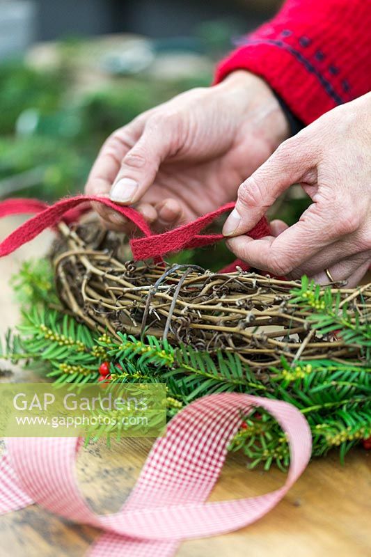 Close up detail of tying a tape handle to a festive wreath