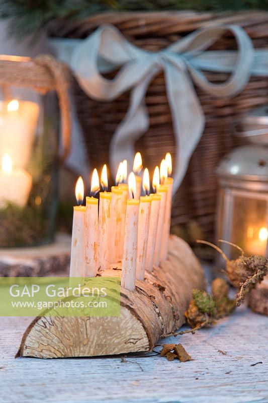 Close up detail of Lit Birch wood candle holder with beeswax candles