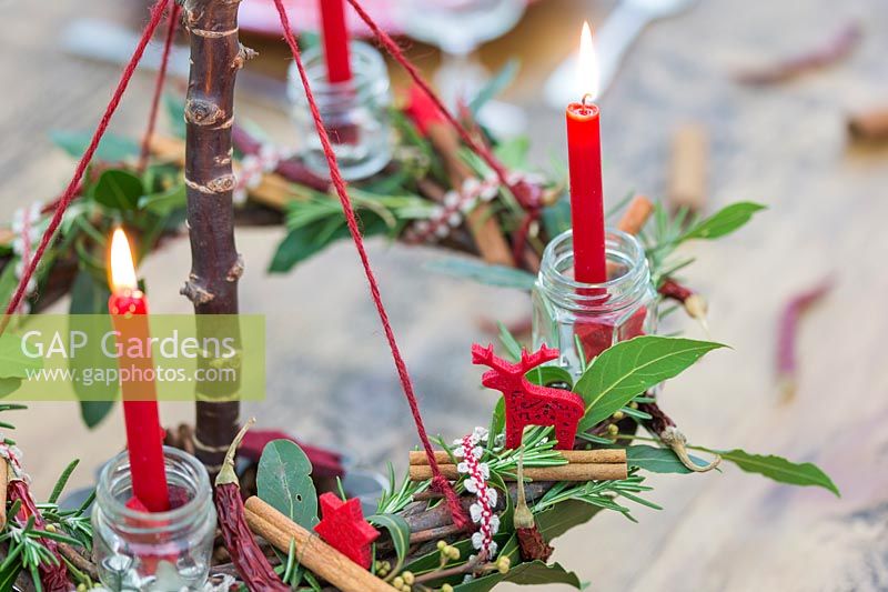 Close up detail of red themed advent candle holder with lit candles as centrepiece in a table setting
