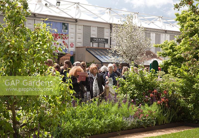 Visitors to the RHS Chelsea Flower Show looking at a Garden on Main Avenue. The Homebase Garden, Designer Adam Frost