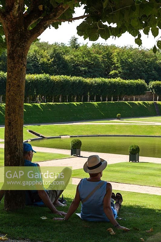 A couple sitting in the shade in the gardens at the Chateau de Villandry, Loire Valley, France. A UNESCO World Heritage Site