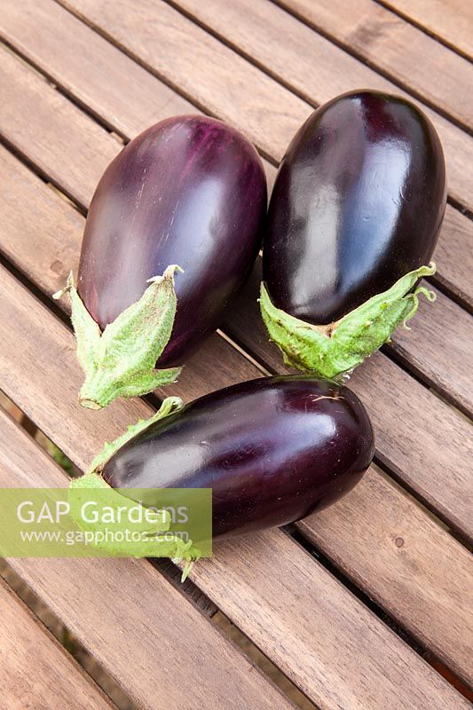 Three aubergines on a wooden table