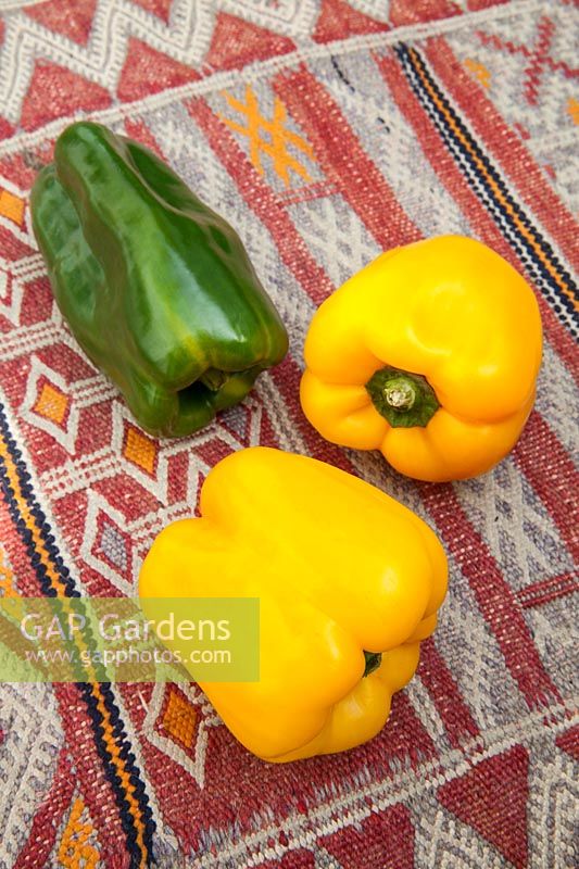 Fresh raw yellow and green peppers on a kilim covered table
