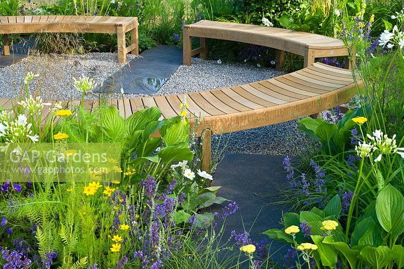 Contemporary garden with gravel path and seating area with wooden benches Designers: Catherine Chenery Barbara Harfleet