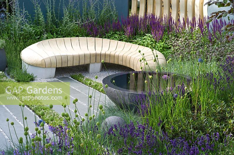 Contemporary urban garden with mixed fencing and organically shaped wooden seat. Designer Rae Wilkinson
