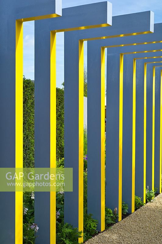 Garden feature of painted upright pergola columns beside a gravel path RHS Hampton Court Palace Flower Show